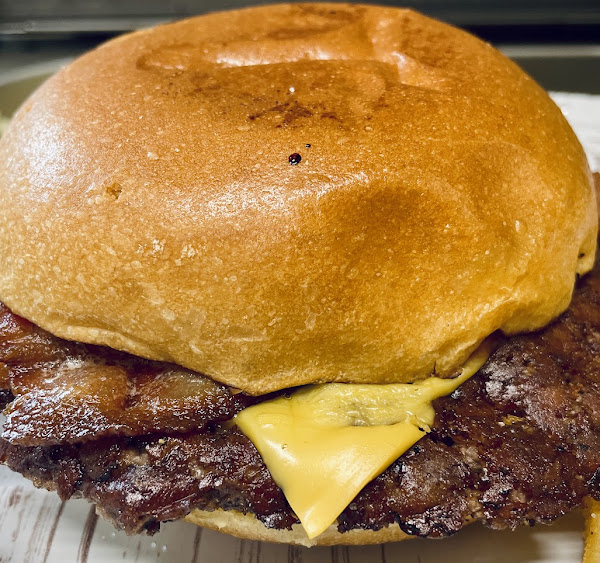 Närbild på en smashburgare med krispig bacon och smält cheddar